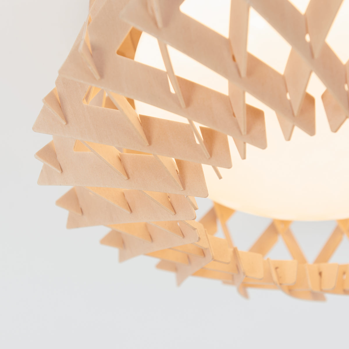 Close-up of the Artika Kiran 13 in. modern LED flush mount light, featuring a geometric wooden frame with interlocking triangles encasing a glowing bulb.