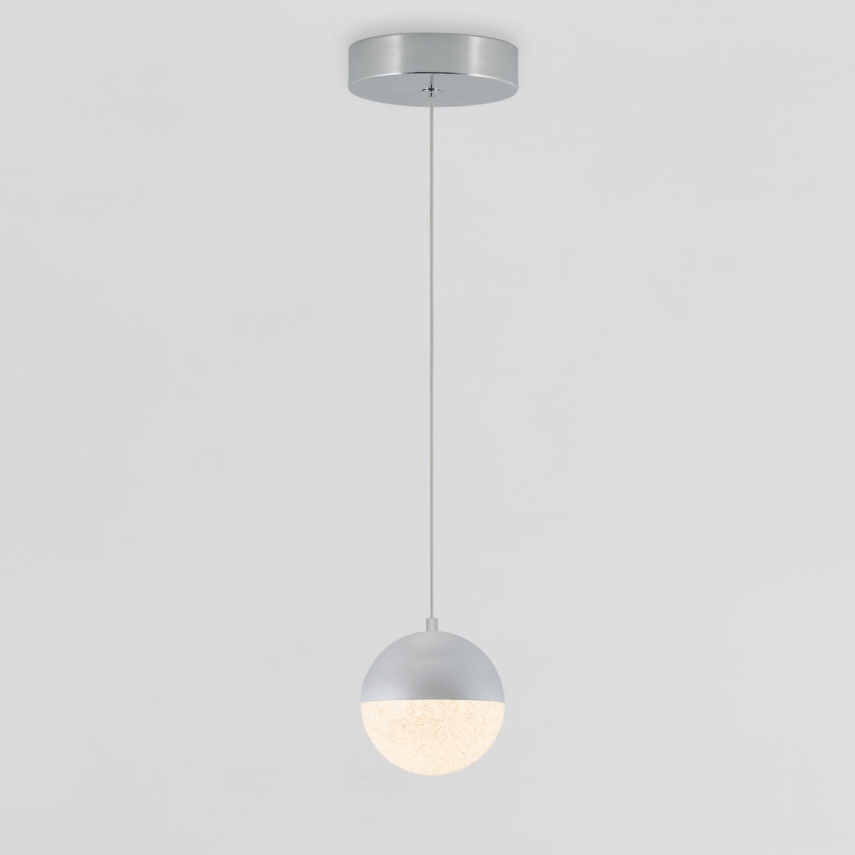 The Artika Sparkle 1 light LED pendant features a round shade with a half-metallic silver and half-glowing white design, suspended by a thin cord from a circular ceiling mount against a plain background.