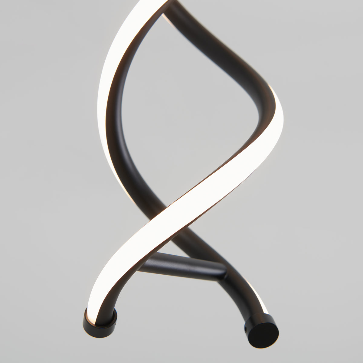 A close-up of Artika’s DNA LED pendant light shows two intertwined, curved, sleek black and white bars against a plain gray background, evoking the look of a double helix.