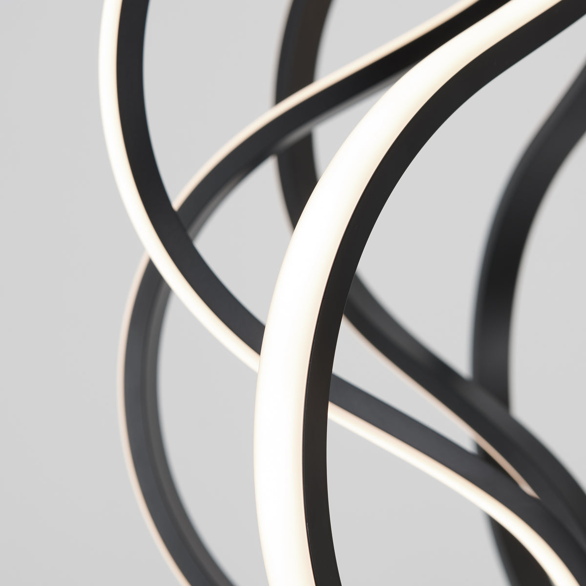The Artika Meridian LED pendant light features curved, intertwined black and white strips in an abstract modern design, set against a plain grey background.