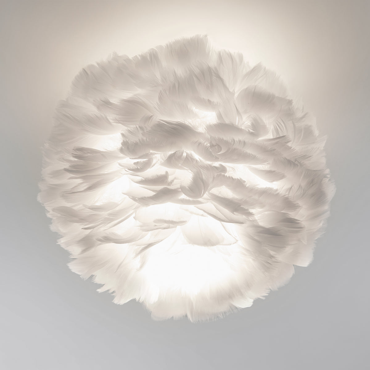 The Artika Plume LED flush mount light features a white, feathered design that softly diffuses light through its layered feathers, evoking a cloud-like ambiance in any room.