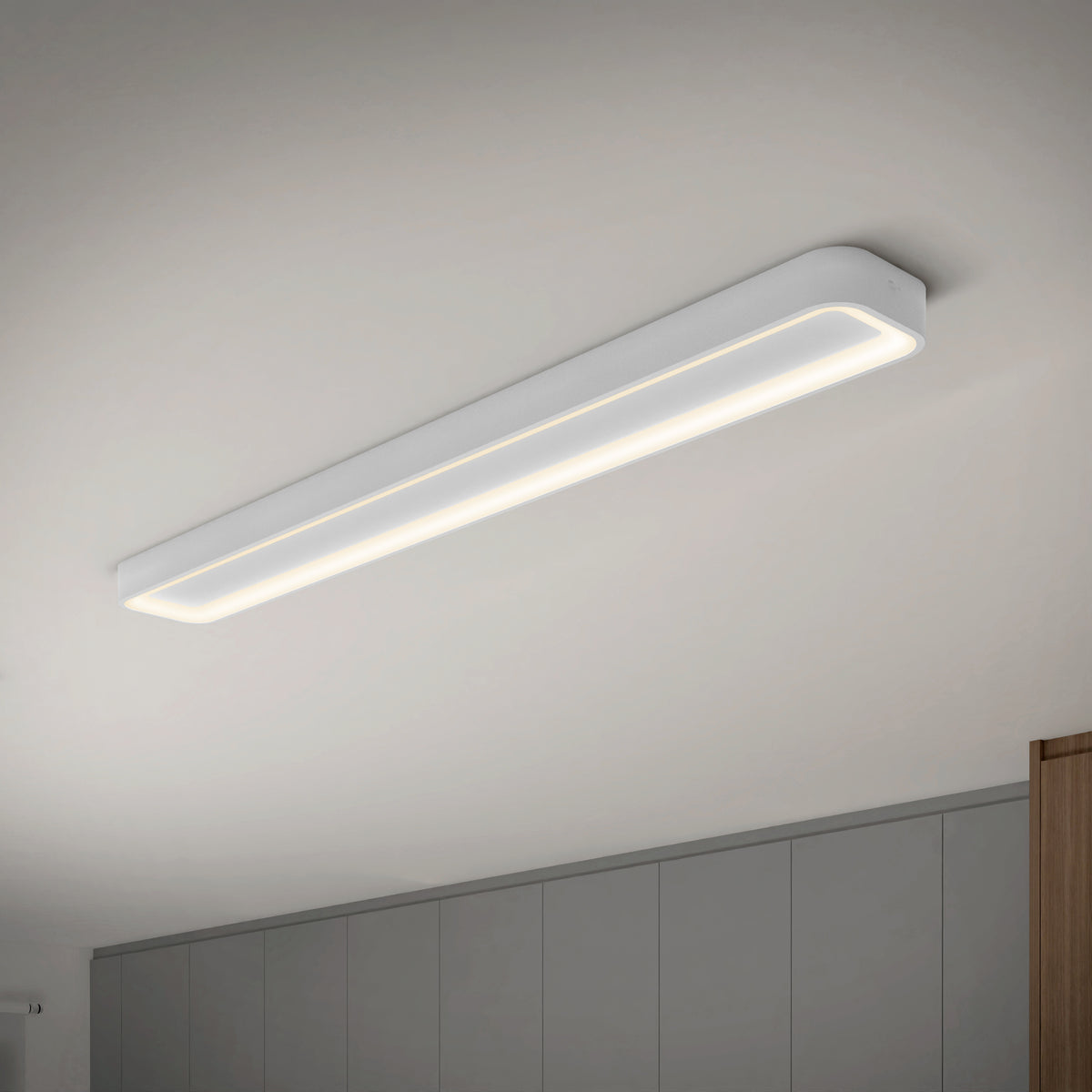 An Artika Aiden 48 in. LED modern flush mount light (5 CCT) is installed on a white ceiling above a room featuring gray cabinets and a glimpse of a wooden panel.