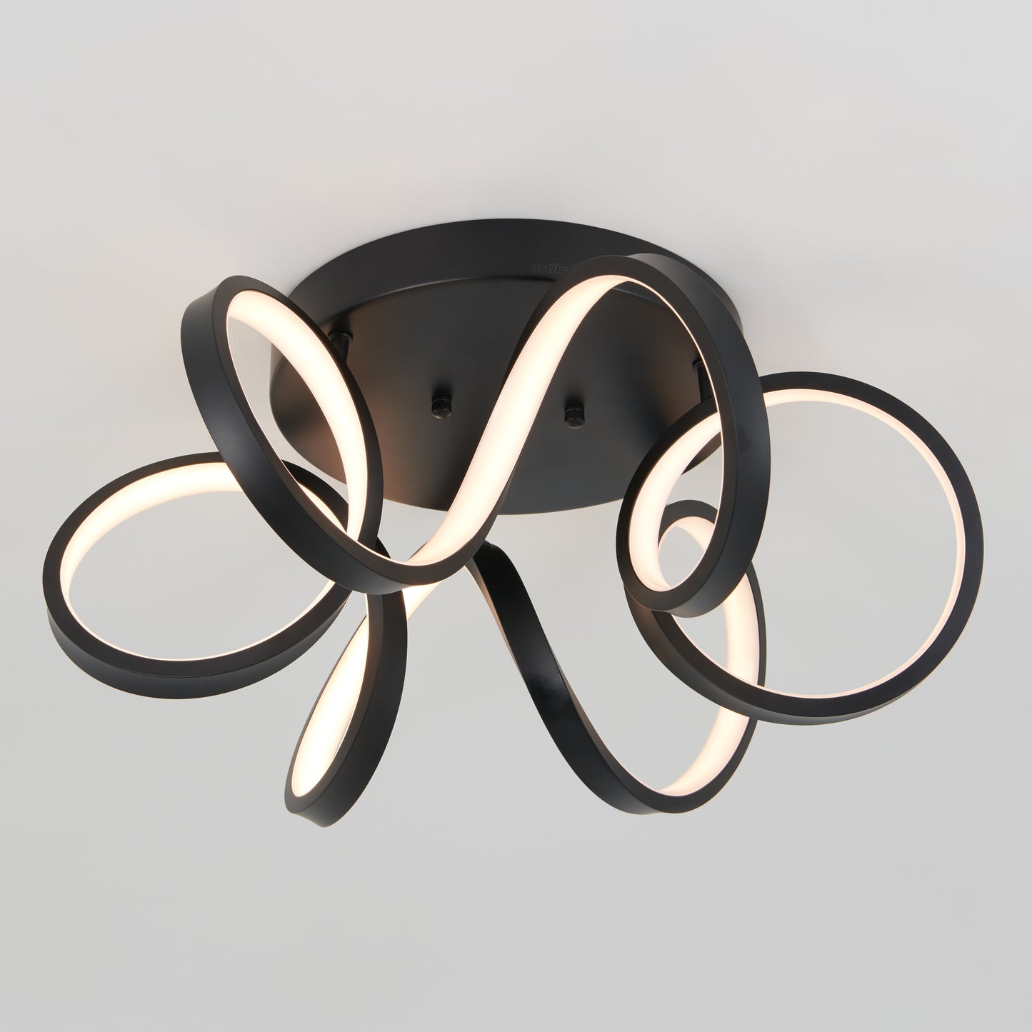The Artika Swirl Ribbon flush mount light features a black base and multiple looping, curved LED strips for an abstract, sculptural look against a plain light gray background.