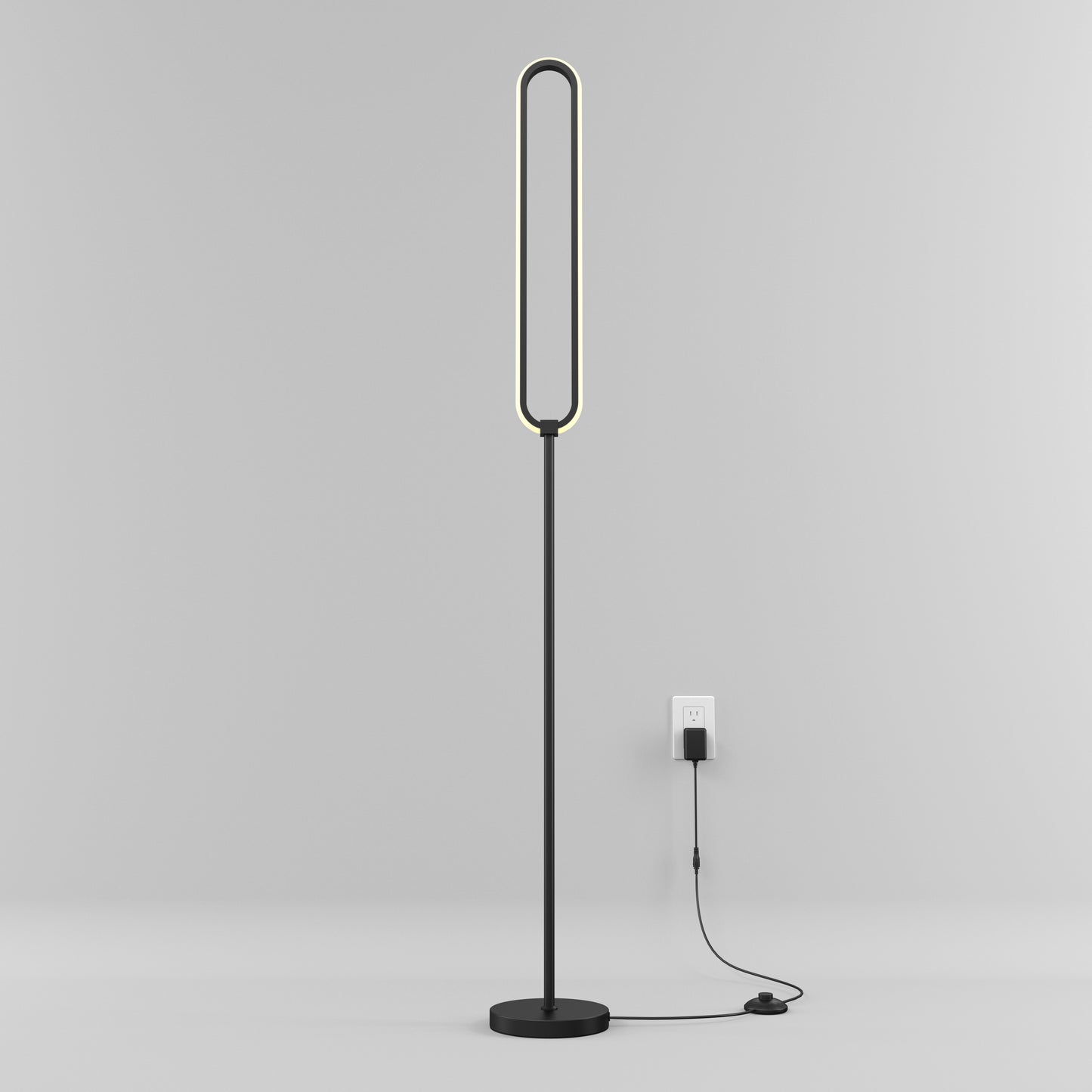 The Artika Leni dimmable LED modern floor lamp features an oval light and flat base, standing plugged into a wall outlet against a plain light gray background.