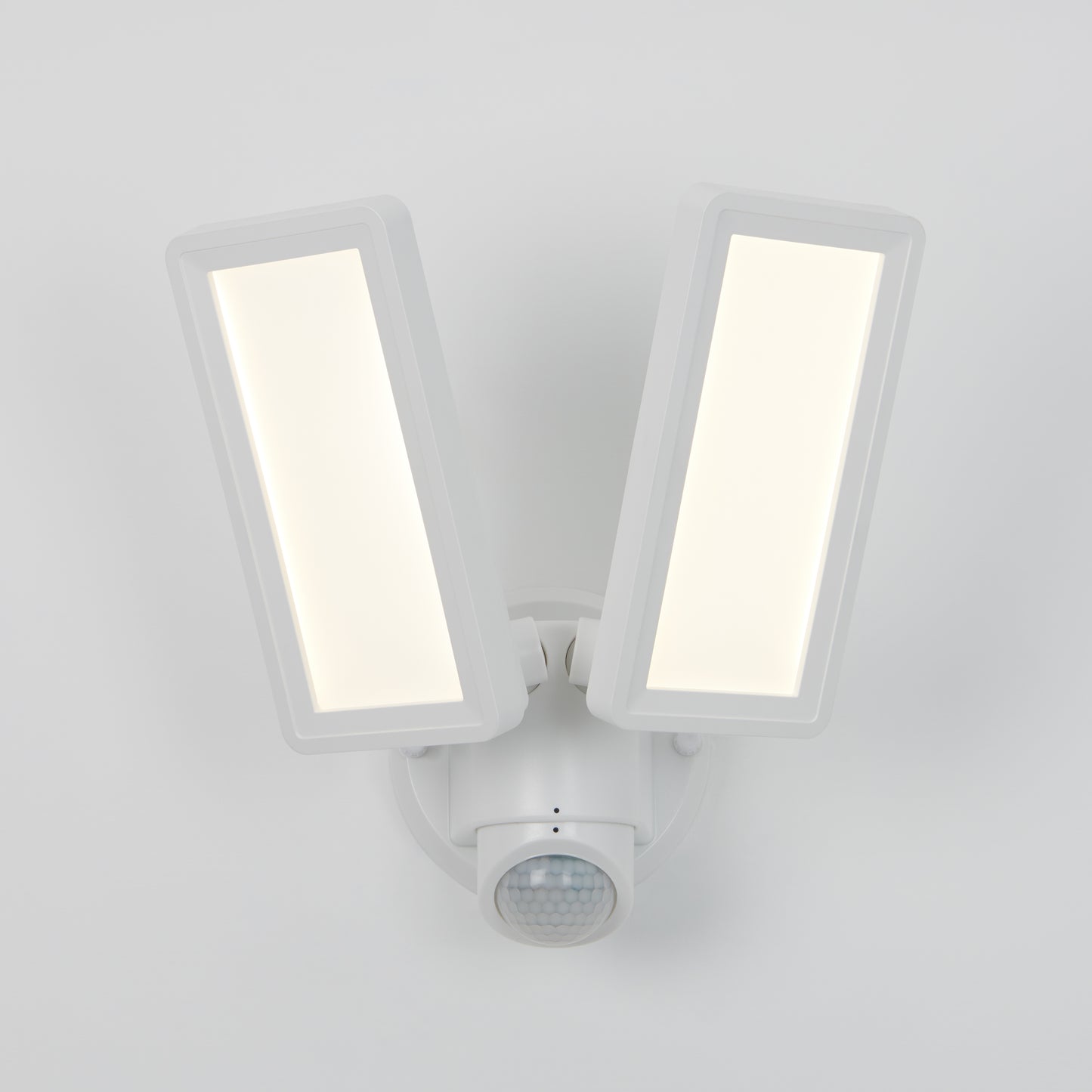 The Artika Sentinel outdoor Flat Panel Security light features two rectangular LED panels and a motion sensor below, all in a sleek white housing mounted on a white wall.