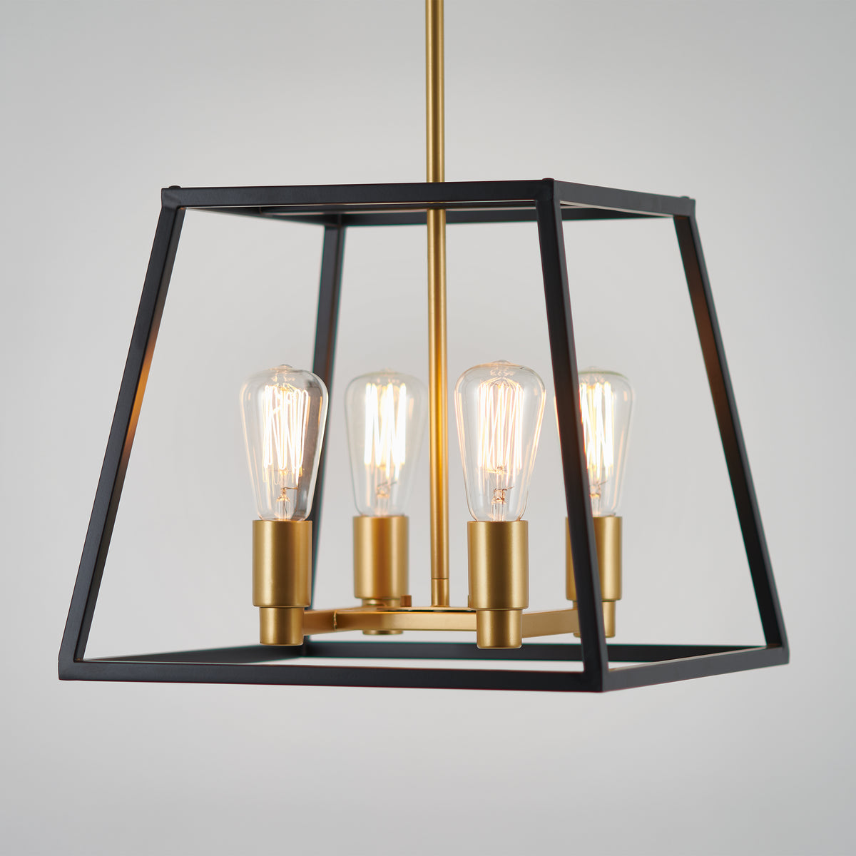 The Carter Square 4-light LED chandelier by Artika showcases a black geometric frame with gold accents and exposed bulbs hanging from a gold rod, creating modern industrial style for any space.