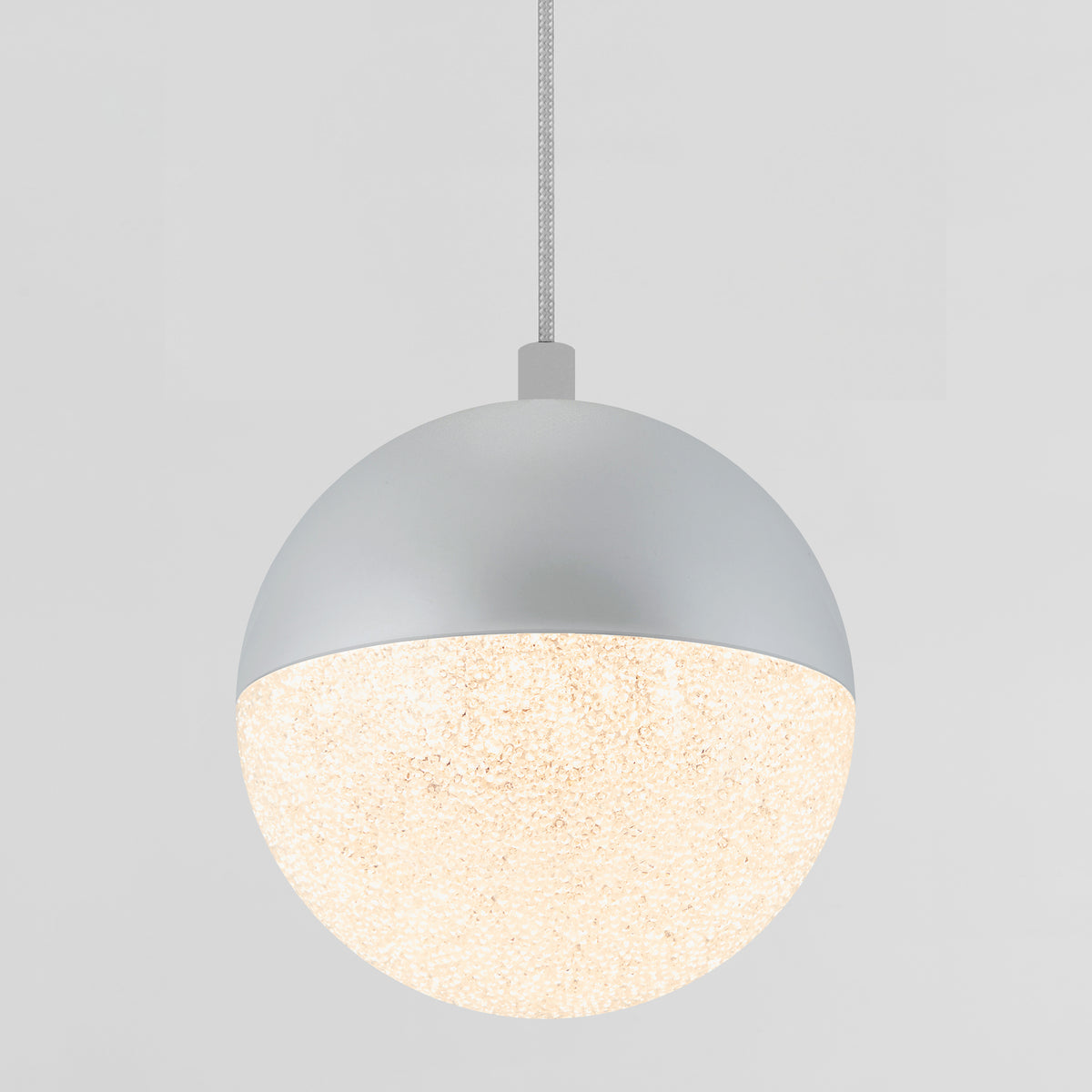 The Artika Sparkle 1 Light LED Pendant features a modern spherical design with a matte silver upper half and a textured, glowing lower half, suspended from a cable against a plain light gray background.