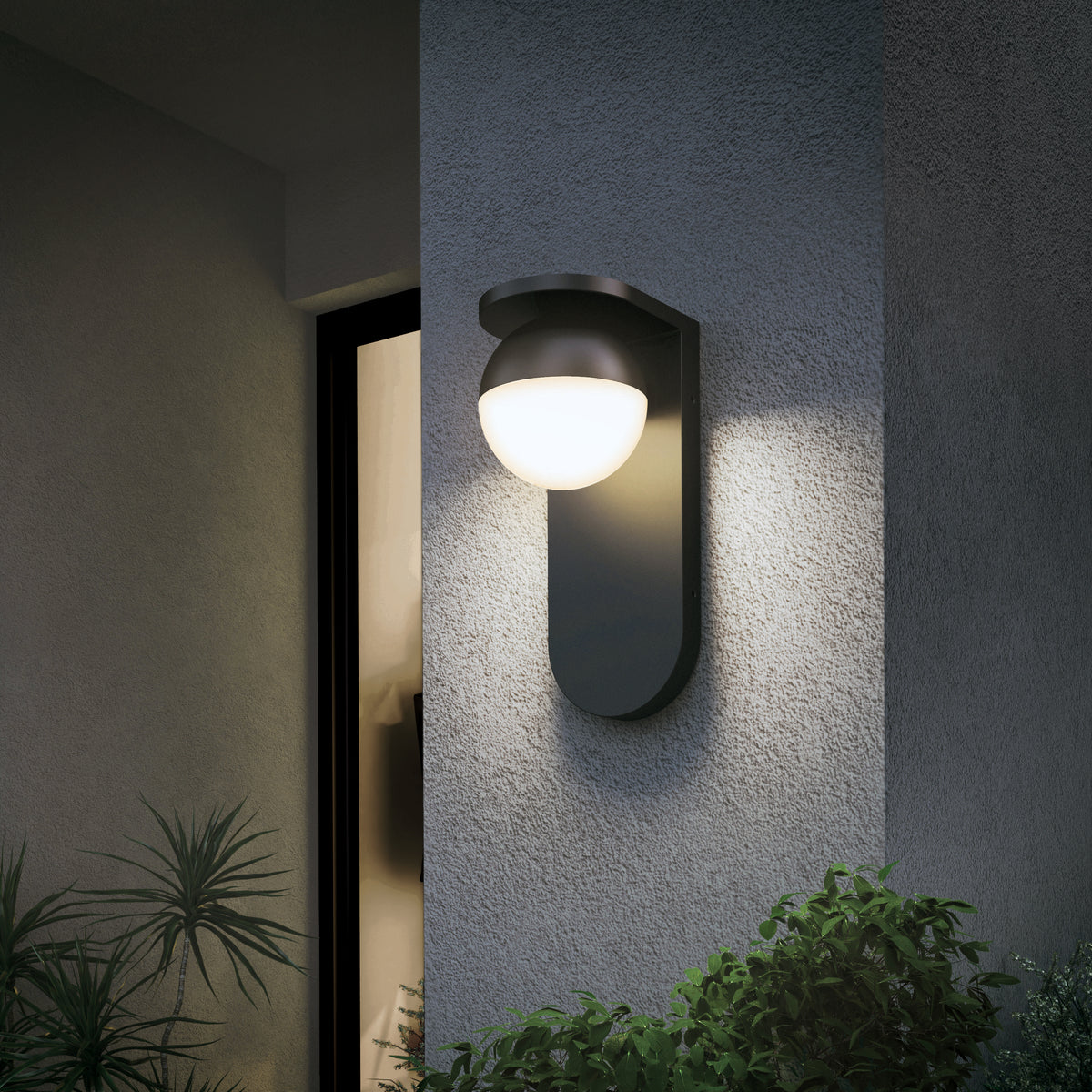 The Artika Bloom indoor-outdoor LED wall light 3 CCT, featuring a round frosted glass shade, is mounted on a textured gray wall by a window, illuminating the area with greenery below.