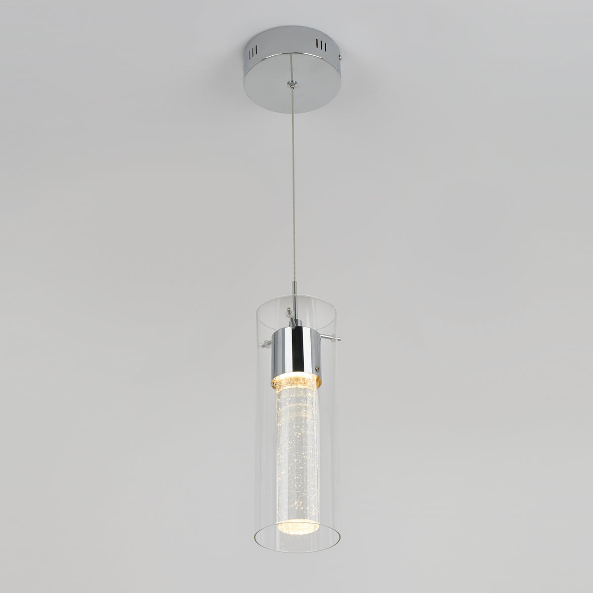 The Essence LED pendant light by Artika features a cylindrical glass shade and chrome fixture, suspended from the ceiling by a slim cable, shown against a plain white background.