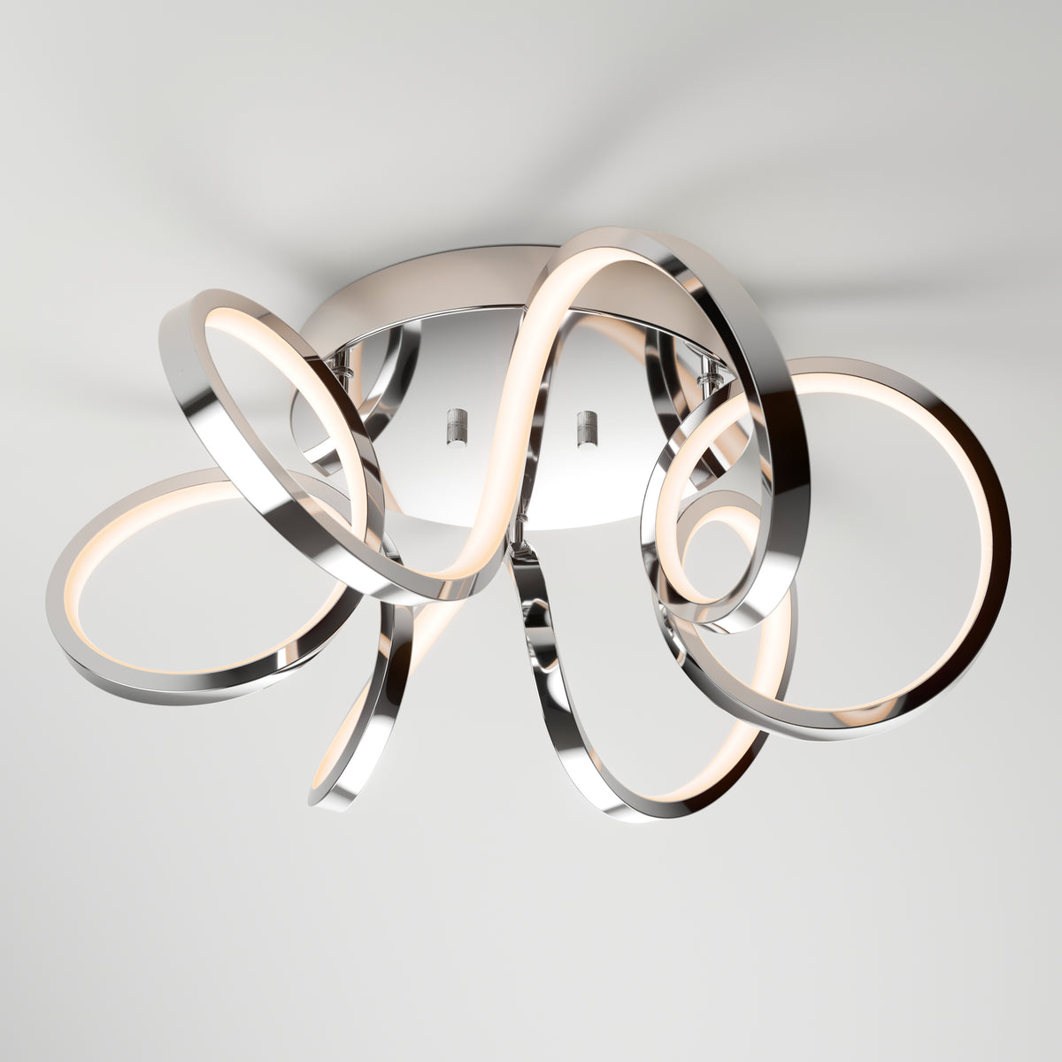 The Artika Swirl Ribbon LED flush mount light features intertwined chrome loops with integrated LED strips on a round base, offering stylish illumination and a modern touch to any contemporary space.