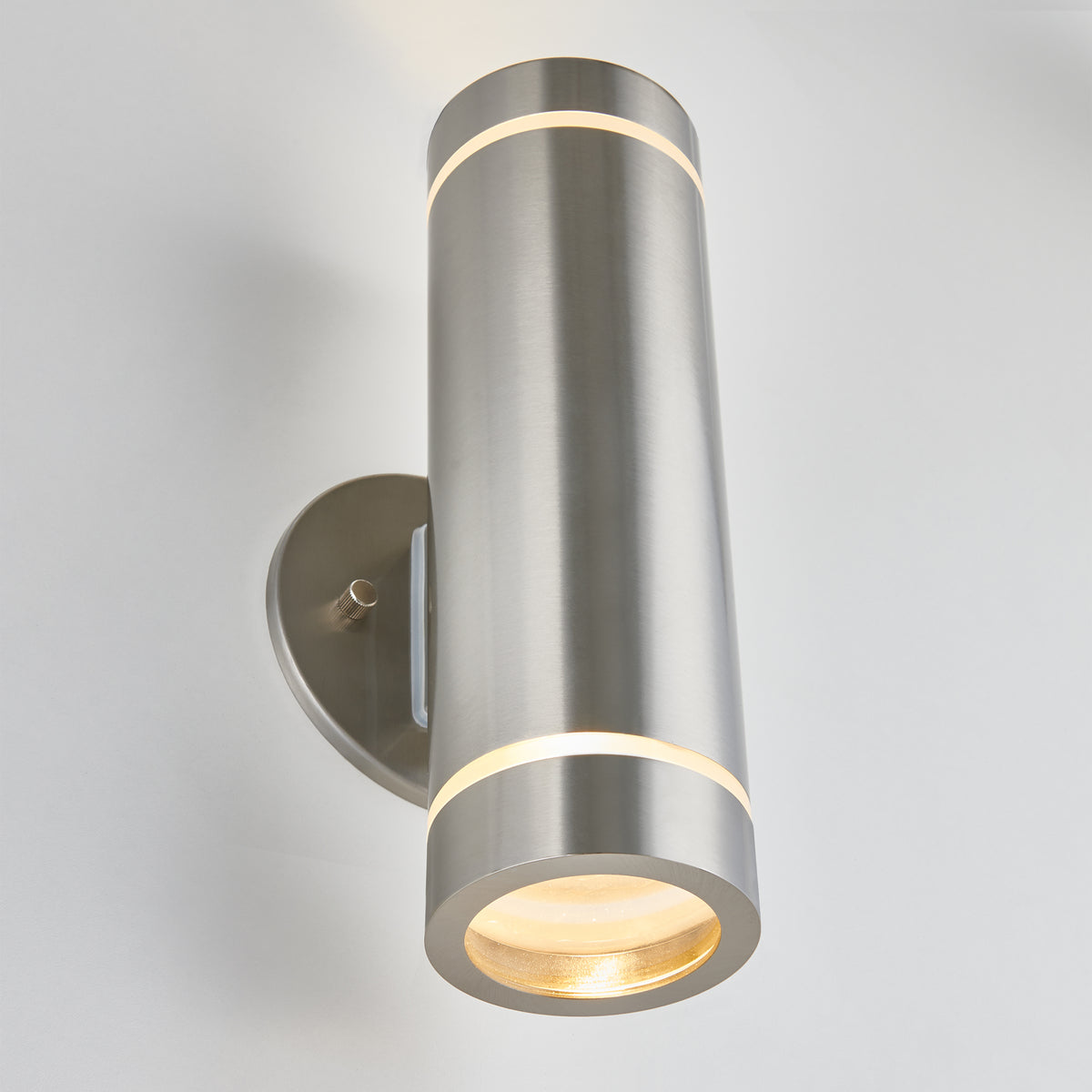 The Artika C7 indoor-outdoor wall light is a modern, rustproof cylindrical sconce with a brushed metal finish, oval backplate, and vertical top-and-bottom lighting—perfect for both indoor and outdoor spaces.