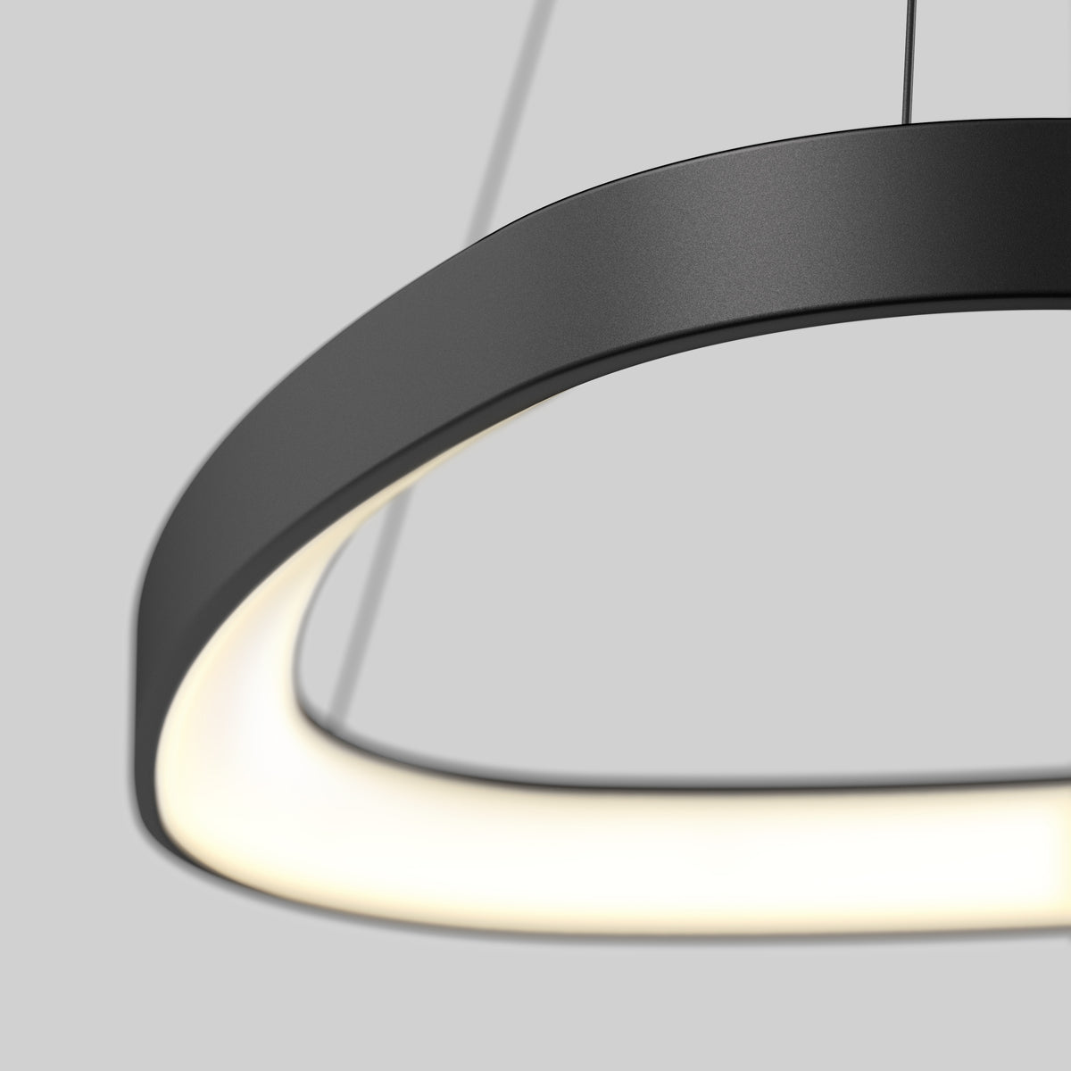 A close-up of the Artika Bjorn modern LED pendant light 5 CCT, featuring a circular black design with a smooth, glowing inner edge, suspended by thin cables against a plain grey background.