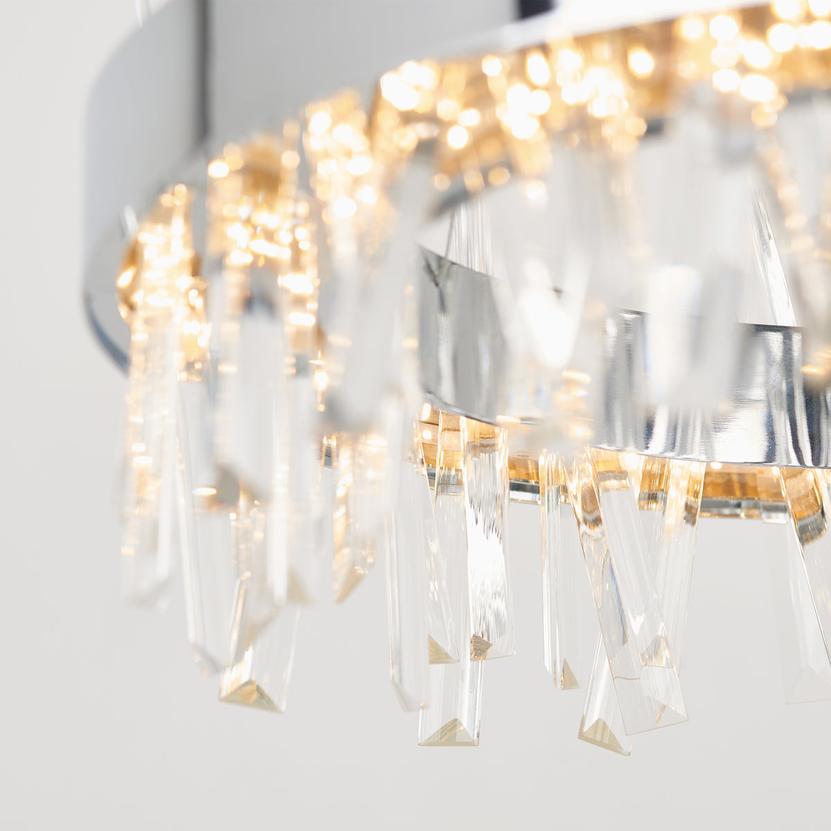 Close-up of the Artika Enchanted LED pendant light featuring hanging crystal prisms and warm lights, casting sparkling reflections against a neutral background.