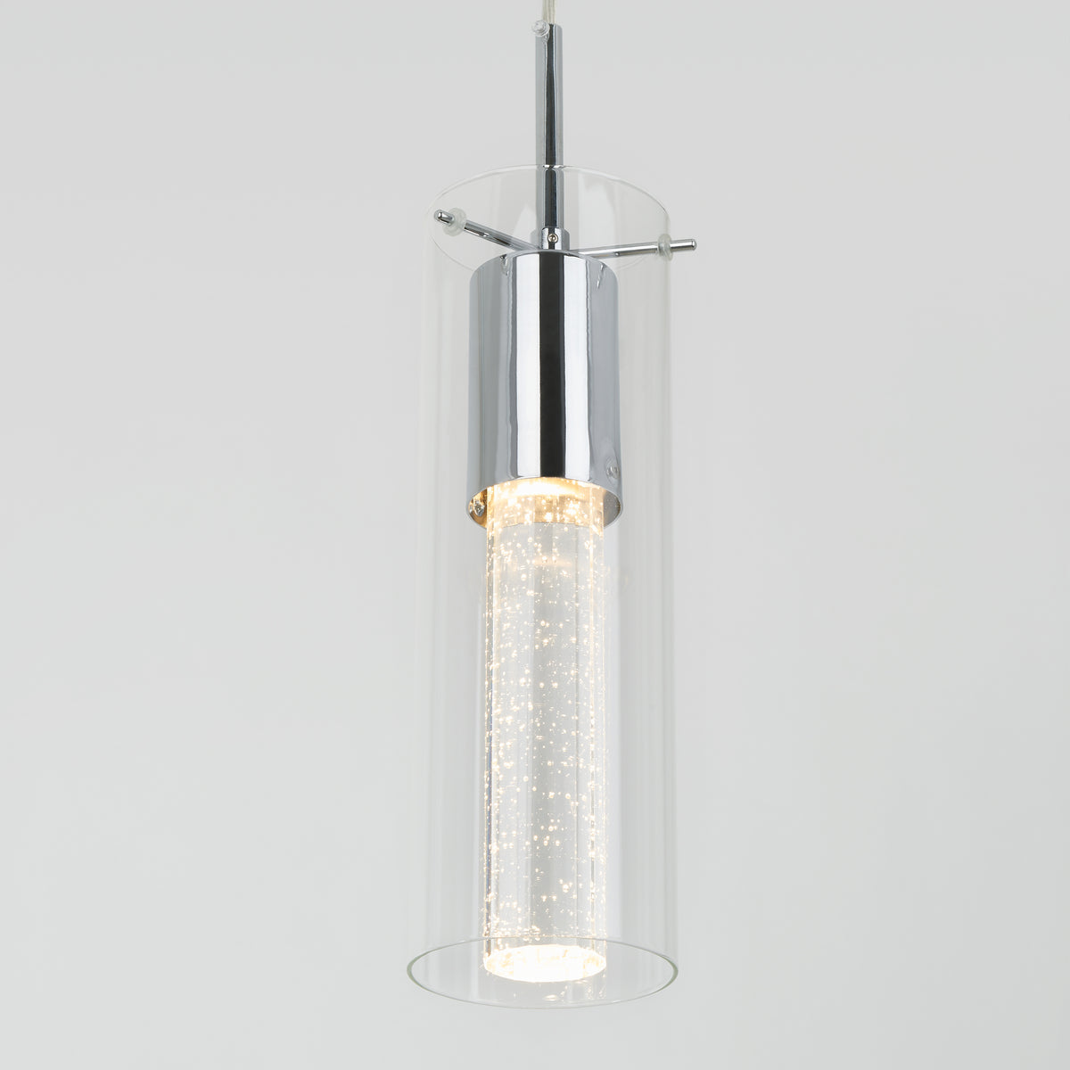 The Artika Bubble Flow 1-light pendant 2 features a modern cylindrical glass shade with chrome accents and an inner frosted tube filled with bubbles, all suspended against a plain light gray background.