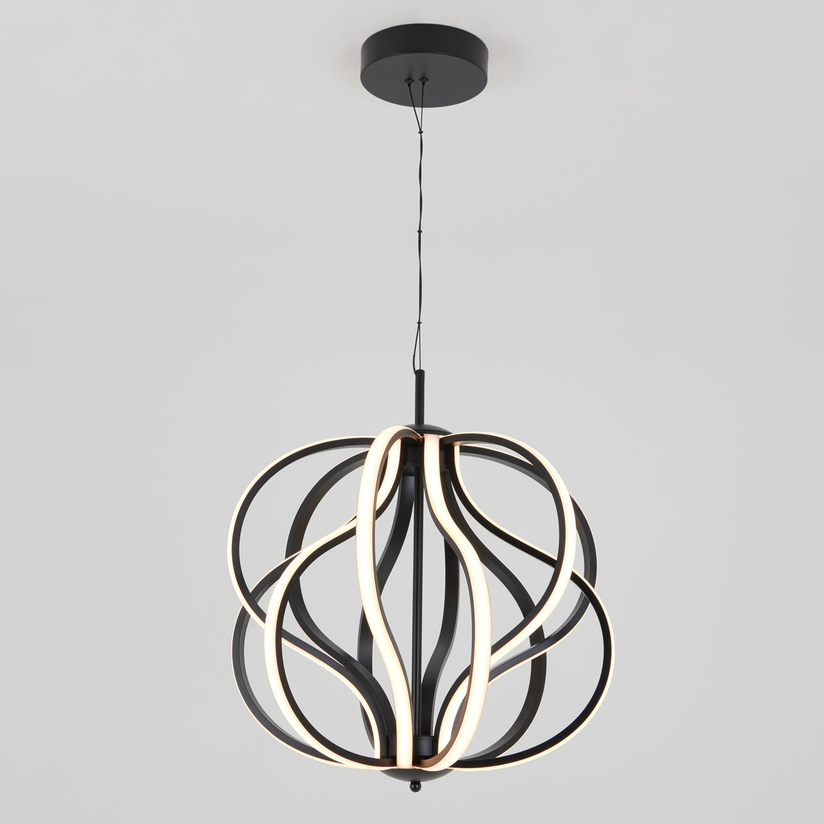 The Artika Meridian LED pendant light showcases intertwined black metal loops with integrated LED strips, suspended from a black ceiling mount against a plain light gray background.
