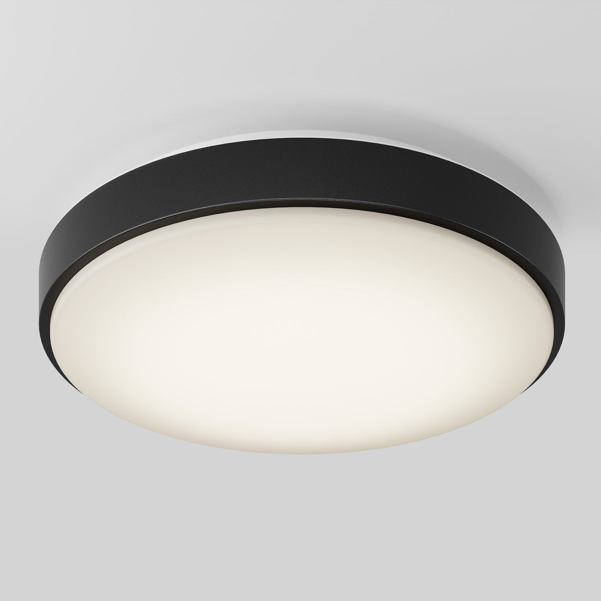 A modern, round ceiling light fixture with a black outer ring and a white, frosted diffuser, mounted on a white ceiling.