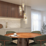 Modern dining area with a round wooden table, four green upholstered chairs, marble backsplash, wood cabinets, gold faucet, hanging glass pendant lights, and a cup with a saucer on the table near a window with sheer curtains.