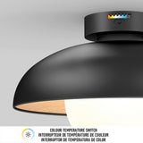 A close-up of a modern black ceiling light fixture with a visible colour temperature switch on the base. A label below describes the switch in English and French.