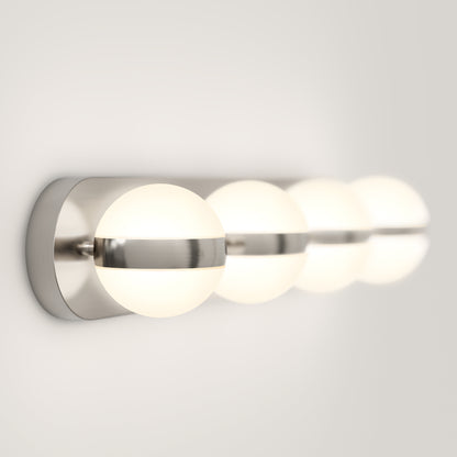 The Artika Baldric LED modern bathroom vanity light features four round frosted glass globes in a horizontal row, each with a brushed metal band, providing a soft, warm glow and offering 3 color temperatures.