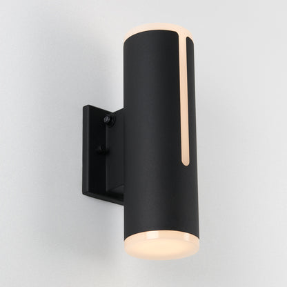 The Artika Linea modern indoor-outdoor LED wall light features a sleek cylindrical black design with a vertical cutout, casting soft white light on a plain light-colored wall.