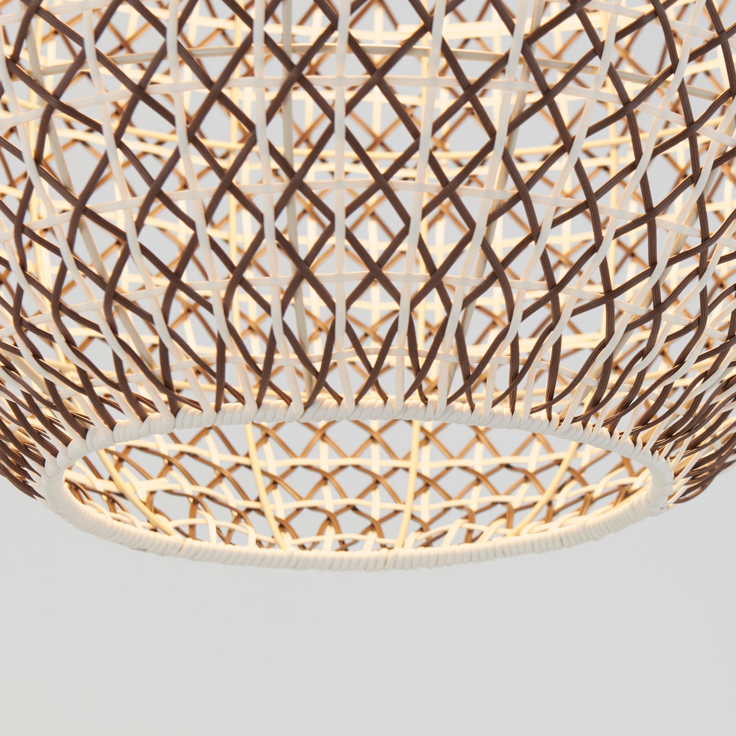 Close-up of the Artika Benson LED pendant light 5 CCT, featuring a woven rattan shade with a geometric lattice design. Its warm internal glow is highlighted against a plain, light-colored background.
