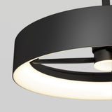 Close-up of a modern, circular black ceiling light fixture with a glowing white inner ring, set against a plain light gray background.