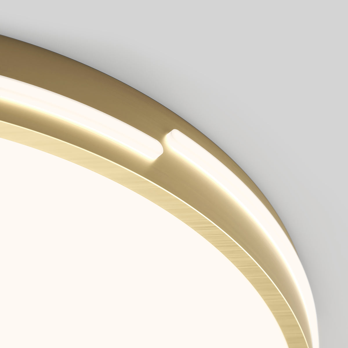 Close-up of a modern circular light fixture with a gold metallic rim and integrated LED strip, mounted on a white ceiling. The fixture emits a soft, warm glow.