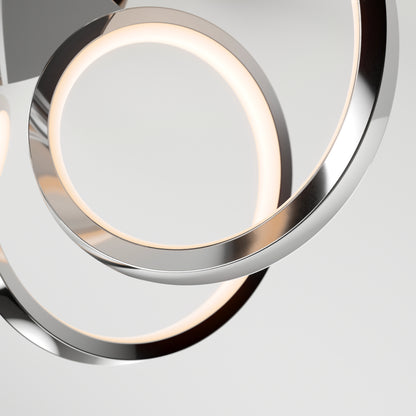 Close-up of the Swirl Ribbon flush mount light by Artika, showcasing overlapping metallic rings with integrated LEDs. The sleek, minimalist design stands out against a plain, light-colored background.