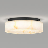 The Artika Clifford 15 in. flush mount light features a modern round design with a frosted white marbled shade, black base, and 5 CCT options, emitting a soft glow against a plain gray background.