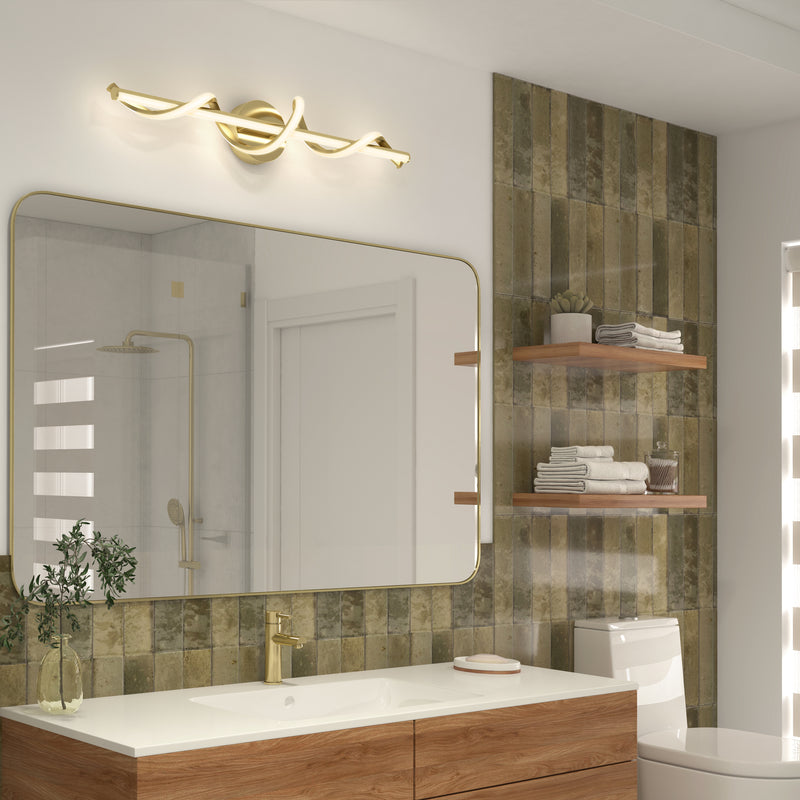 Modern bathroom with a large rectangular mirror, gold faucet, and Artika Coda modern LED bathroom vanity light 5 CCT. Greenish-brown tiles line the wall, with wooden shelves over the toilet next to a wooden vanity with a white countertop.