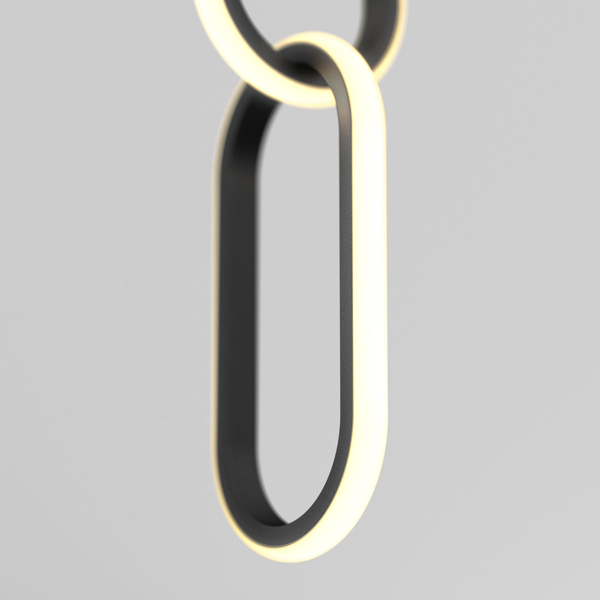A close-up of two interlocking, oval-shaped black rings with illuminated white edges, suspended against a plain light grey background. The design is minimalistic and modern.
