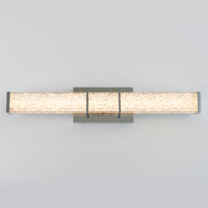 The Artika Royale LED bathroom vanity light features a modern wall-mounted design with a rectangular textured glass shade and metallic frame, casting a soft, even glow against a light gray background.