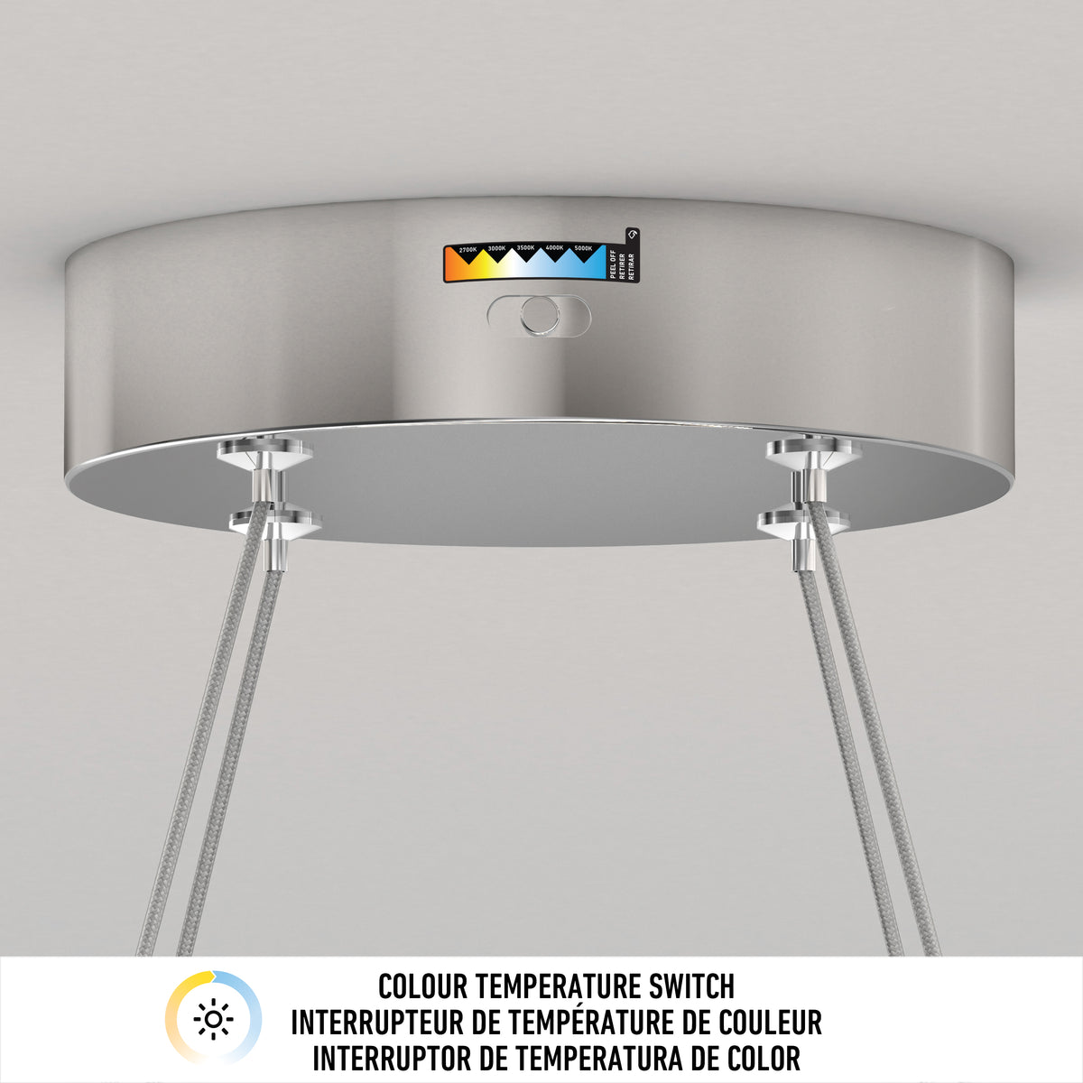 A close-up of a ceiling-mounted light fixture with a color temperature switch, labeled with a range from warm to cool tones. Metal cables suspend the fixture. Text below describes the color temperature switch in three languages.