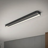 A modern, rectangular black ceiling light fixture with a continuous LED strip is mounted on a white ceiling above gray cabinets in a minimalist room.