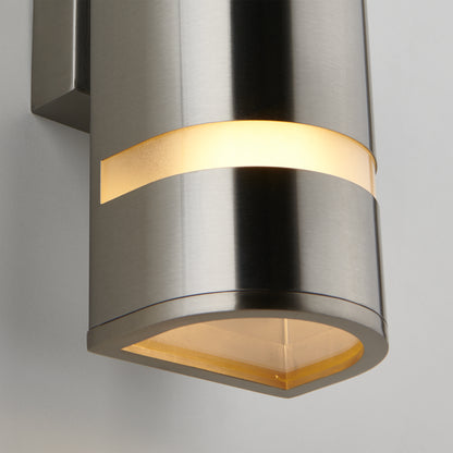 A close-up of the Artika Q1 indoor-outdoor wall light, a modern stainless steel sconce with a cylindrical design and horizontal cutout emitting warm light, mounted on a white wall.