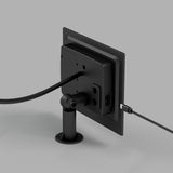 A black electronic device is mounted on a stand, viewed from the back. Two cables are connected to the device: one thick cable and one thin cable, both plugged into separate ports. The background is plain gray.