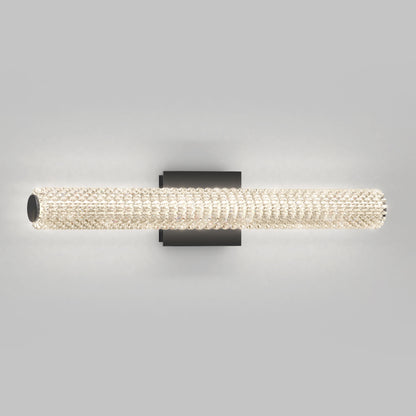 The Artika Exalto LED bathroom vanity light features a modern, cylindrical crystal-covered design that emits a soft glow. It has a simple black rectangular mount, perfect for adding elegance to any space.