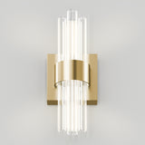 Wall-mounted light fixture with a modern design featuring vertical glass rods radiating from a central brass base and band, emitting soft, diffused light against a plain white background.