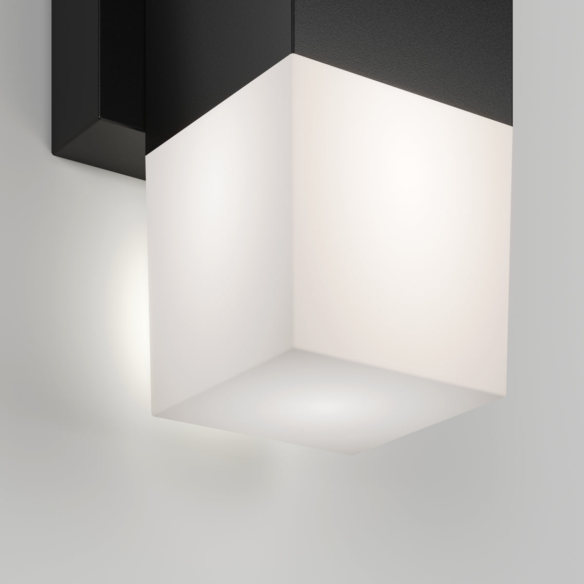 The Artika Lennox indoor-outdoor LED wall light 3 CCT features a modern cube design with a black top and frosted white bottom, casting a soft, diffused glow on walls.
