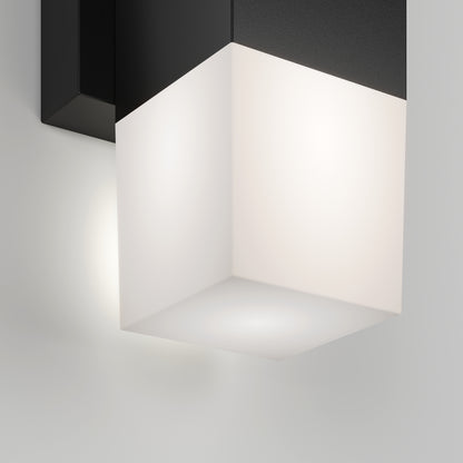 The Artika Lennox indoor-outdoor LED wall light 3 CCT features a modern cube design with a black top and frosted white bottom, casting a soft, diffused glow on walls.