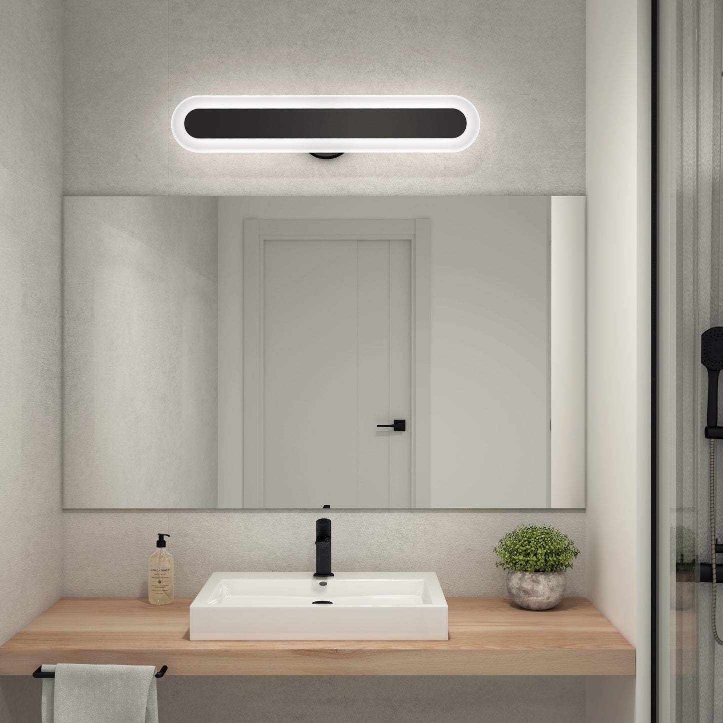 A minimalistic bathroom features a wooden countertop, white rectangular sink, soap dispenser, potted plant, large mirror with towel, and the Artika Pista modern LED bathroom vanity light 5 CCT above it. Walls and door are white.