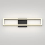 A modern wall sconce with a rectangular, open-frame LED light in a horizontal orientation, mounted on a black square base against a plain light-colored wall.