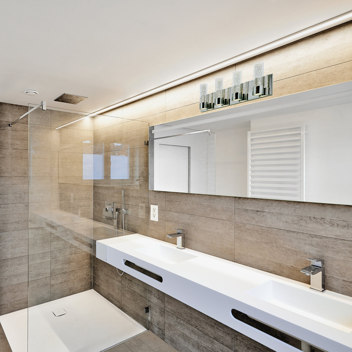Modern bathroom with beige tile walls, a large mirror, double white sinks, sleek faucets, a glass shower enclosure, wall-mounted lights, and a white towel warmer. The design is minimalistic and clean.