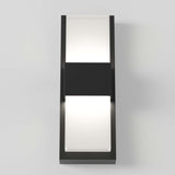 A modern rectangular wall sconce with a black frame and two frosted white panels, one on the top and one on the bottom, emitting a soft light, mounted on a light gray wall.