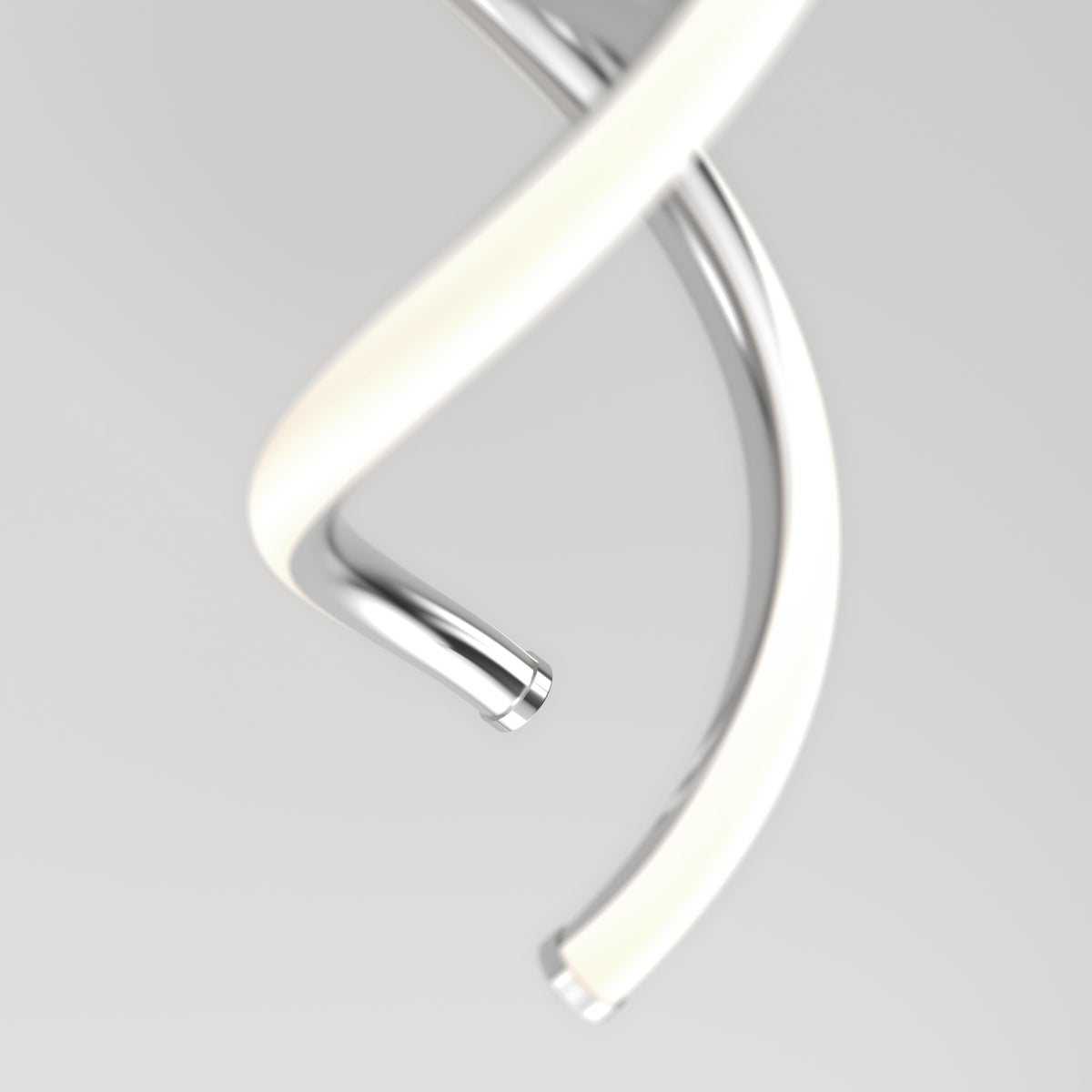 A close-up of two intertwined, spiral metal tubes against a plain, light background. One tube is shiny silver, and the other appears to be covered with a soft, white material.