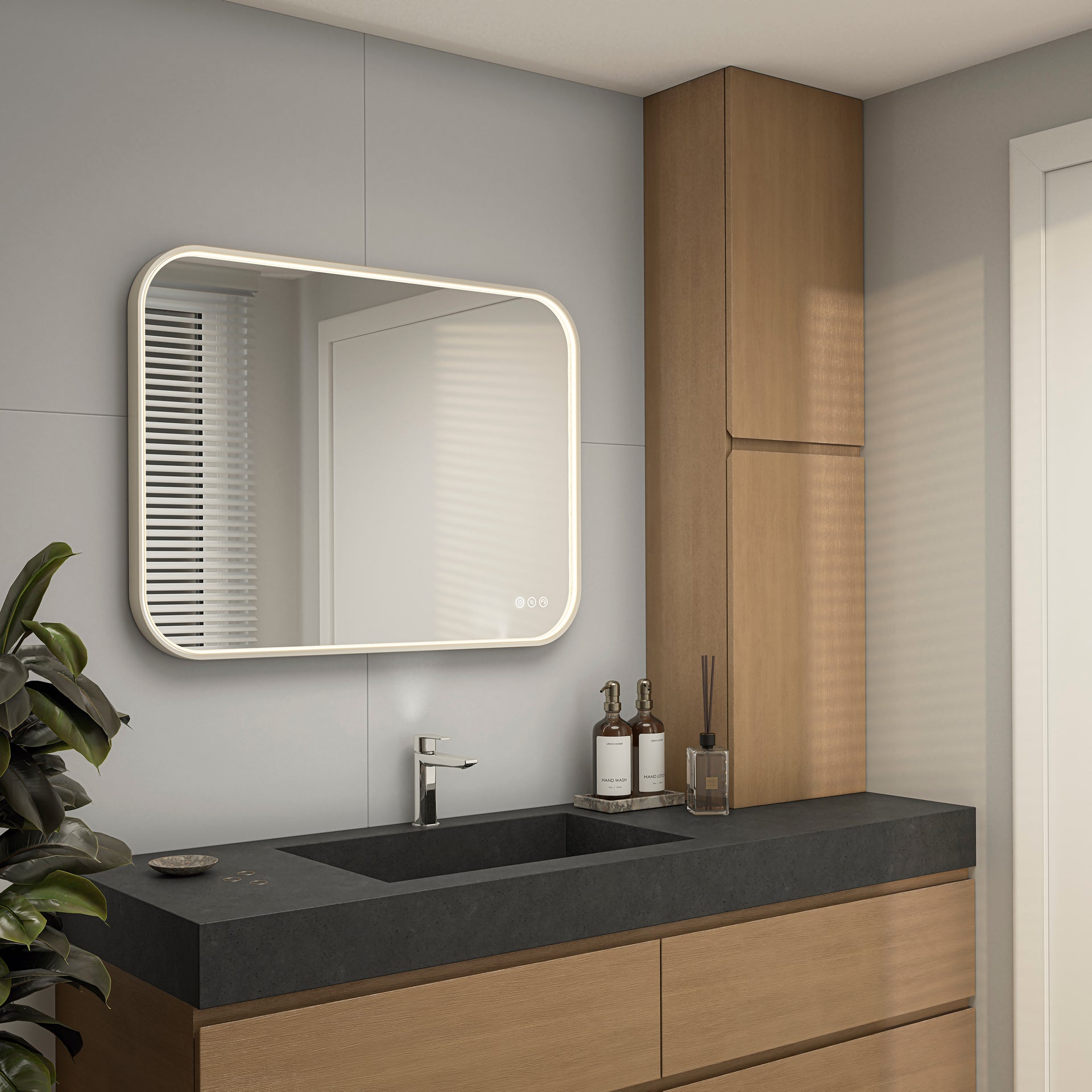 A modern bathroom with light wood cabinets, a black countertop with built-in sink, accessories beside the faucet, and an Artika Royce Dimmable LED Mirror (3 CCT, horizontal/vertical mount). Light streams through a window.
