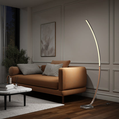 A modern living room with a tan leather sofa, striped and plain cushions, a large plant, and the Artika Arc LED Floor Lamp emitting soft light. A marble coffee table and a minimalist wall painting complete this cozy space.