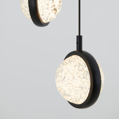 Close-up of two Avalon 4-light LED pendants by Artika, featuring textured glowing glass centers and black circular frames, suspended from the ceiling against a plain light gray background.