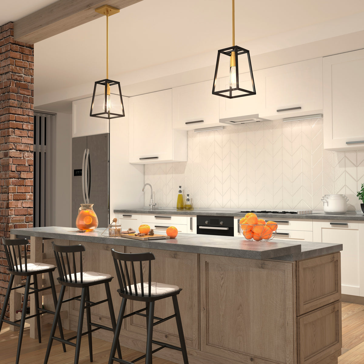 A modern kitchen with white cabinets, subway tile backsplash, a large wooden island with three black chairs, pendant lights, and bowls of oranges as decor. Exposed brick and stainless steel appliances are visible.