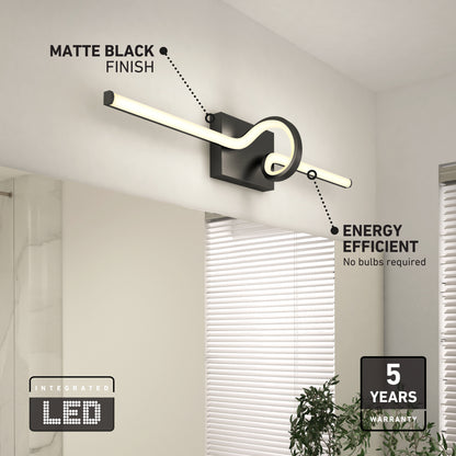 The Artika Bowtie modern LED bathroom vanity light 5 CCT features a matte black, circular design, is energy efficient with integrated LEDs—no bulbs needed—and comes with a 5-year warranty. A window and plant are nearby.